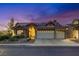 Charming single-story home at dusk with a tile roof, three-car garage, solar panels, and drought-resistant landscaping at 3088 Paseo Mountain Ave, Henderson, NV 89052
