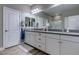 Bathroom featuring double sinks with gray counter tops, large mirror, and white cabinets at 379 Mano Destra Ln, Henderson, NV 89011