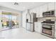 A modern kitchen with stainless steel appliances, white cabinets, and sliding glass doors to the backyard at 3966 Crystal Trip Ct, Las Vegas, NV 89129