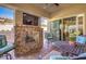 Inviting covered patio with a stone fireplace, TV, ceiling fan and comfortable seating area at 489 Open Hill Ave, Henderson, NV 89011