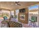 Inviting covered patio with a stone fireplace, TV, ceiling fan and comfortable seating area at 489 Open Hill Ave, Henderson, NV 89011