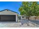 Charming single-story home with gravel landscaping, a tree, and a black two-car garage at 5279 Consul Ave, Las Vegas, NV 89142