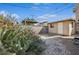 Backyard featuring a rock garden with cacti, a covered patio, block wall and beige outbuilding under a blue sky at 600 Federal St, Henderson, NV 89015