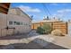 Backyard with gravel landscaping, wood fence, green shrubbery, and side of home under a blue sky at 600 Federal St, Henderson, NV 89015