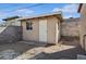 Sideyard view features a tan outbuilding with white door, a window, block wall and gravel landscaping at 600 Federal St, Henderson, NV 89015