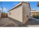 Sideyard with tan stucco siding, gravel landscaping, wood fence, and side of home under a blue sky at 600 Federal St, Henderson, NV 89015