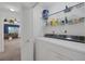 Functional laundry area with washer, dryer, shelving, and storage, leading to a carpeted living room at 6804 Elm Creek Dr # 202, Las Vegas, NV 89108
