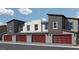 Townhome exterior featuring red garage doors, a modern facade, and clean landscaping in a sunny setting at 7351 Kyle Cove Dr # Lot 208, North Las Vegas, NV 89084
