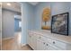 Hallway with neutral walls, tile flooring, and white cabinets beneath counter space with art display at 754 Tallgrass St, Las Vegas, NV 89138
