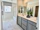 Bright bathroom featuring double sinks, gray cabinetry, shower over tub and neutral tile at 10376 Joaquin Fire St, Las Vegas, NV 89141