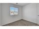 A view of a bedroom with gray carpeting, white walls, and a window that brings in natural light at 10773 Bede Ct, Las Vegas, NV 89166