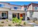 Inviting two-story townhome features an orange front door, low maintenance landscaping, and a concrete walkway at 10773 Bede Ct, Las Vegas, NV 89166