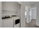 Modern laundry room equipped with washer, dryer, storage shelf, and a door to another room at 10773 Bede Ct, Las Vegas, NV 89166
