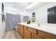 Bathroom with double sinks, wood cabinets, shower with blue curtain and light wood flooring at 11134 Casala Ct, Las Vegas, NV 89141