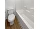 The well-lit bathroom features a pristine white toilet, bathtub, and wood-style floors at 2125 Stone Well Rd, North Las Vegas, NV 89031