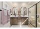 An elegant bathroom features dual vanities, modern fixtures, and a glass-enclosed shower, all beautifully lit at 2151 Noble Perch St, Las Vegas, NV 89138