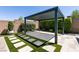 A modern black pergola sits over artificial turf squares on a stone patio with manicured landscaping at 2680 Nevada Agave Ln, Las Vegas, NV 89138