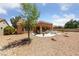 Spacious backyard featuring a covered patio, desert landscaping, and mature trees for shade at 2925 Lotus Hill Dr, Las Vegas, NV 89134