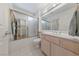 This bathroom features a glass-doored shower, white tile floor and a large sink with a large mirror above it at 2925 Lotus Hill Dr, Las Vegas, NV 89134