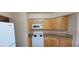 Bright kitchen featuring white appliances, wood cabinetry, and light granite countertops at 3151 Soaring Gulls Dr # 2058, Las Vegas, NV 89128