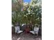 Landscaped patio featuring metal chairs and a small table, enclosed by mature foliage, and gray stone wall at 3464 Twilight Star Dr, Las Vegas, NV 89117