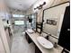 Elegant bathroom featuring double sinks, marble-style floors and walls, and a glass-enclosed shower at 5041 Portraits Pl, Las Vegas, NV 89149