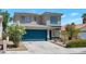 Two-story home features blue garage door, desert landscaping, and concrete driveway at 5204 Padua Way, Las Vegas, NV 89107