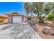 Single-story home featuring a garage, desert landscaping, and a well-lit walkway at 5257 Sunbury Ave, Las Vegas, NV 89122