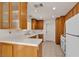 Galley kitchen with oak cabinets, white appliances, white countertops, and light tile flooring at 5400 Paul Kurtz Way # 105, Las Vegas, NV 89108