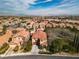 Expansive aerial view of a neighborhood with tile-roofed homes and mountain views in the distance on a bright day at 556 Caribbean Palm Dr, Las Vegas, NV 89138