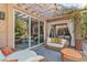 Stylish patio with comfortable wicker furniture, a pergola for shade, and views of the home's interior through glass doors at 556 Caribbean Palm Dr, Las Vegas, NV 89138