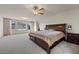 This bedroom has large windows with carpet, a ceiling fan, and a large bed at 6618 Tangled Vines Ave, Las Vegas, NV 89139