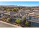 View of homes with gray stucco, dark gray roofs, lovely landscaping, and garages in quiet neighborhood at 6618 Tangled Vines Ave, Las Vegas, NV 89139