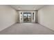 Open living space featuring light gray walls, neutral carpet and access to the balcony at 6618 Tangled Vines Ave, Las Vegas, NV 89139