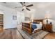 This is a bedroom with wood floors, a ceiling fan, a wooden sleigh bed, and matching bedside tables with lamps at 715 Orange Plume Walk, Henderson, NV 89011