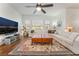 Comfortable living room with a plush white sectional, leather ottomans, ceiling fan, and a flat screen television at 715 Orange Plume Walk, Henderson, NV 89011