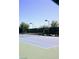 Well-maintained tennis court with blue and green surface, surrounded by trees and a fence under a clear blue sky at 7727 Widewing Dr, North Las Vegas, NV 89084