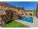 Backyard pool with a large rock waterfall, lush plants, and clear blue sky at 8 Via Tiberina, Las Vegas, NV 89011