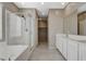 Bright bathroom features double sink vanity, a soaking tub with shower, tiled floor, and neutral color walls at 8486 Insignia Ave # 101, Las Vegas, NV 89178