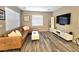 Inviting living room with a leather sectional sofa, wood-look flooring, sleek entertainment center, and natural light at 8534 Insignia Ave # 101, Las Vegas, NV 89178