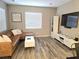 Inviting living room with a leather sectional sofa, wood-look flooring, sleek entertainment center, and natural light at 8534 Insignia Ave # 101, Las Vegas, NV 89178
