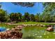 Beautiful pond framed by large rocks, lush greenery, and mature trees, creating a tranquil and scenic outdoor space at 9305 Hollycrest Dr, Las Vegas, NV 89117
