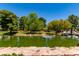 Scenic pond surrounded by mature trees, lush green spaces, and a stone border, offering a serene natural environment at 9305 Hollycrest Dr, Las Vegas, NV 89117