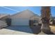 View of the home, driveway, and two-car garage with desert landscaping at 1325 Fiesta Grande Ct, North Las Vegas, NV 89031