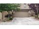 Two-car garage with a wide driveway and manicured trees in front of a two-story home at 167 Desert Pond Ave, Henderson, NV 89002