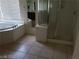 Bright bathroom with a corner tub and separate shower, featuring neutral tile floors at 206 Valerian St, Henderson, NV 89015