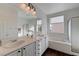 Bright bathroom featuring double sinks, a large mirror, and separate tub and shower at 2261 Evening Lights St, Henderson, NV 89052