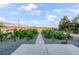 Landscaped backyard showcasing a walkway lined with young trees under a bright, partly cloudy sky at 2261 Pampa Ave, Pahrump, NV 89048