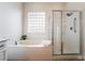 Clean, white bathroom with a soaking tub, glass-enclosed shower, and bright window at 2365 Black River Falls Dr, Henderson, NV 89044