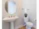 Powder room featuring a pedestal sink, round mirror, and modern fixtures at 2365 Black River Falls Dr, Henderson, NV 89044